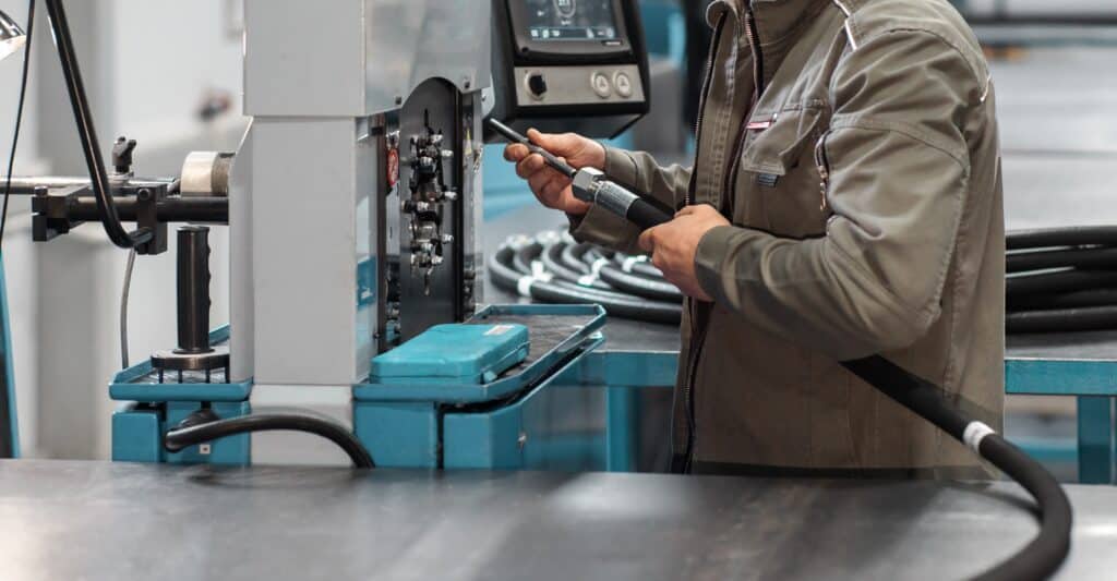A,worker,crimps,a,high,pressure,hydraulic,hose,on,the